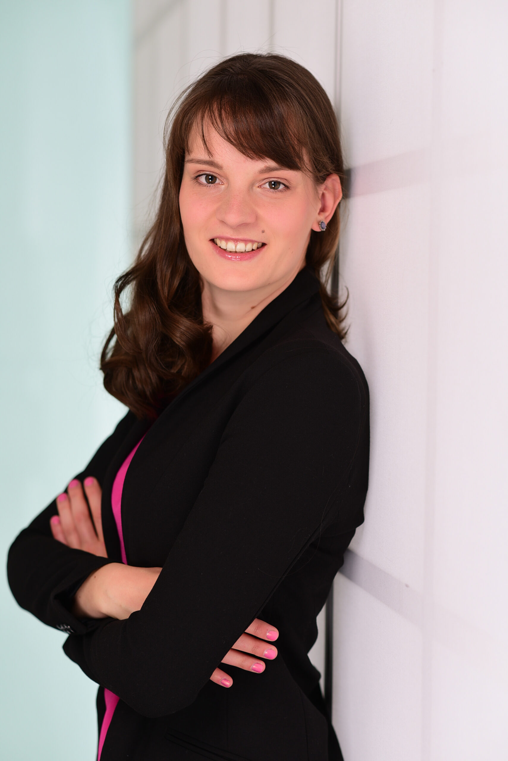 Auf dem Bild sieht man Lisa Gerth, die mit dem Rücken an einer Wand lehnt und in die Kamera lächelt.