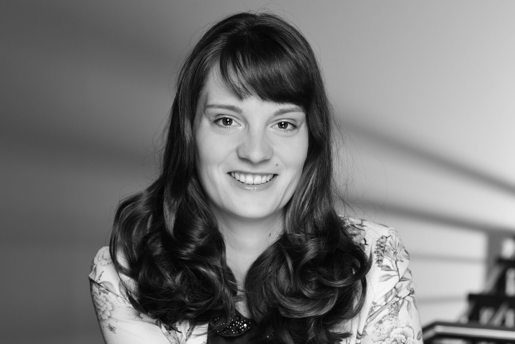 Auf dem Bild sieht man Lisa Gerth, die in die Kamera lächelt. Es ist nur ihr Kopf und Oberkörper zu sehen. Das Bild ist schwarz-weiß.